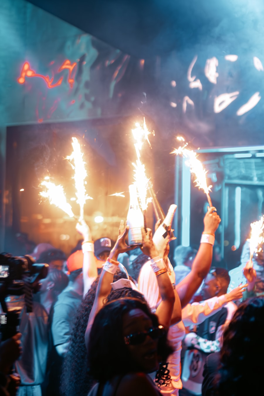 Bottles with sparklers raised above a celebrating crowd
